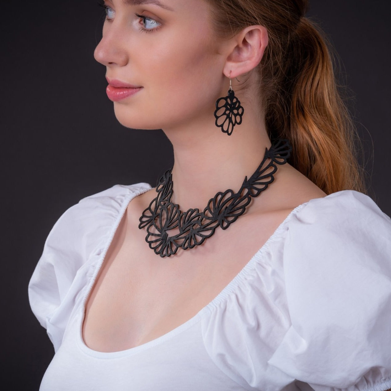 Model wearing Paguro Upcycle black floral statement upcycled vegan flower necklace and matching earring