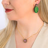 Paguro Upcycle reclaimed wood earrings shaped like green leaves worn on a woman with matching necklace