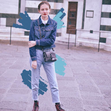 Woman wearing denim jacket and jeans carrying black vegan handbag by Paguro Upcycle outdoors