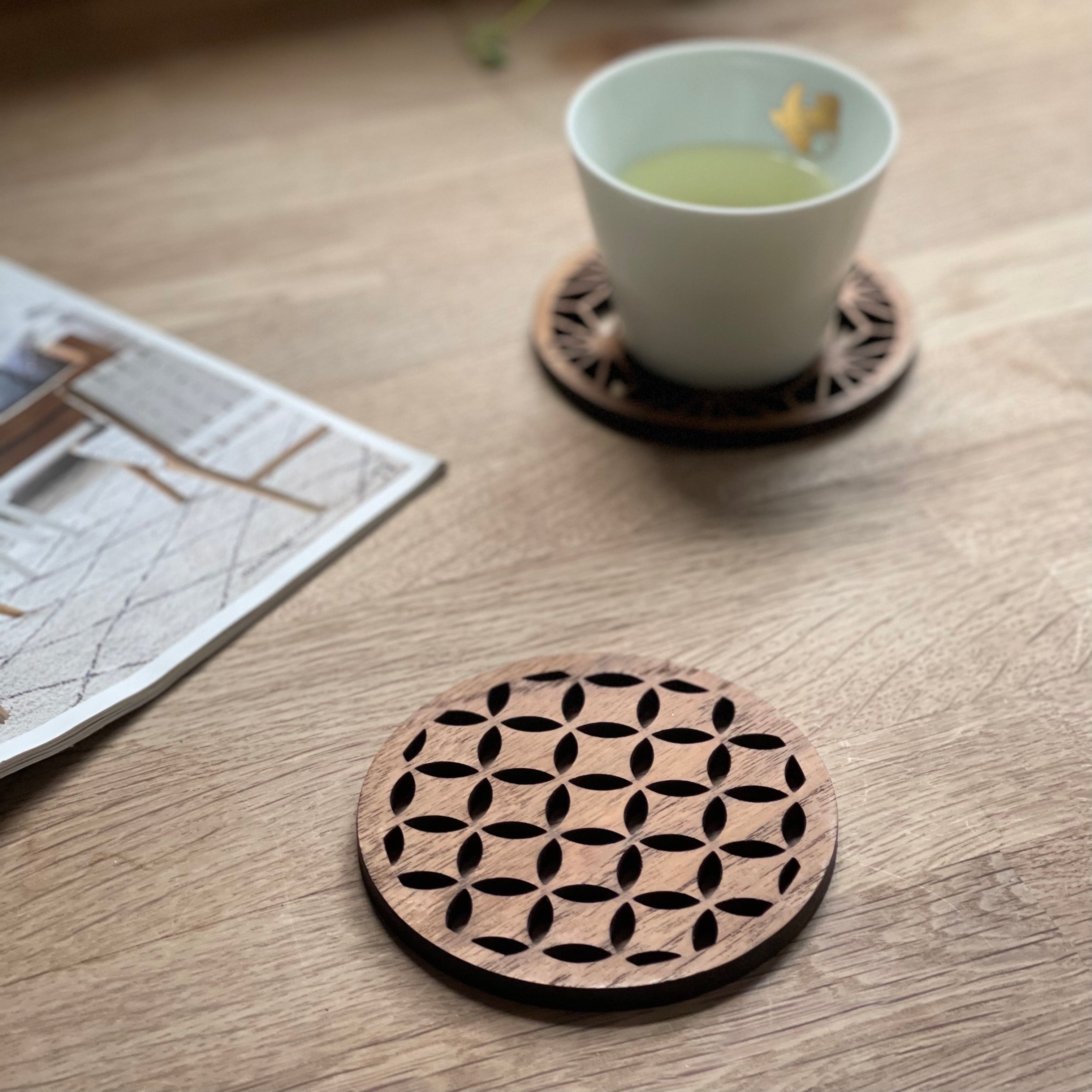 Japanese pattern drink coasters by Paguro Upcycle made of wood with intricate cutout design on a wooden table