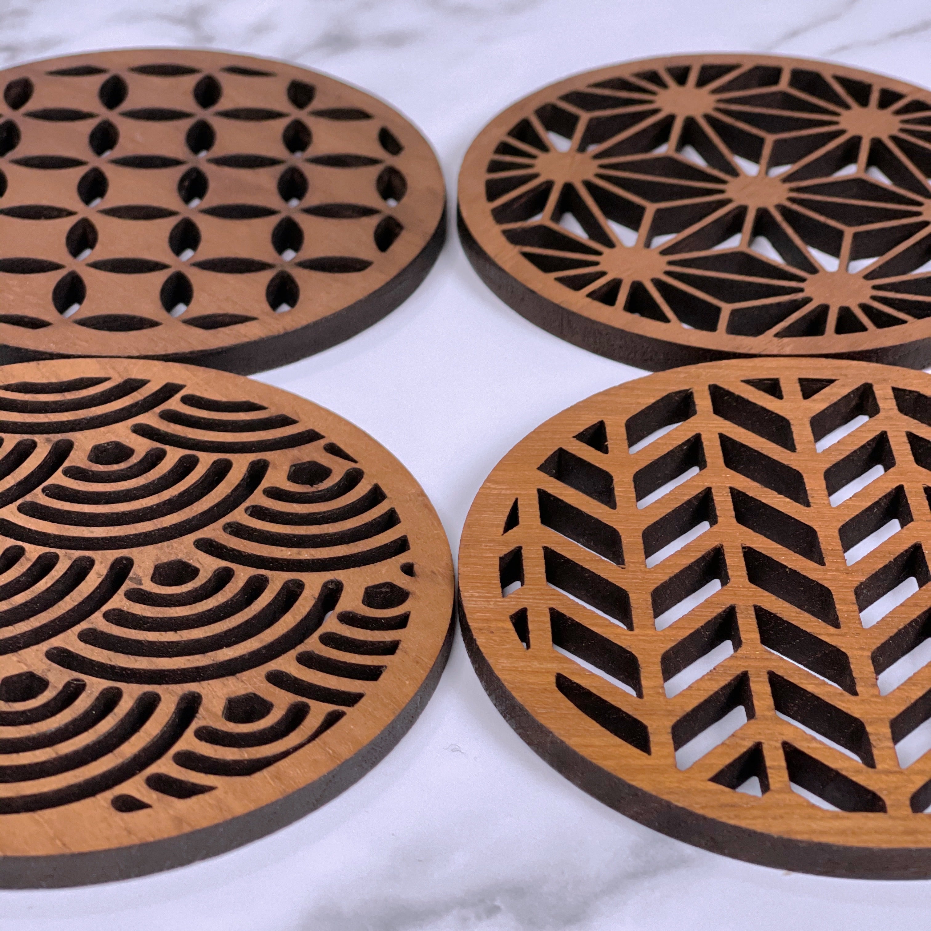 Set of four Paguro Upcycle wooden Japanese pattern drink coasters with intricate cut-out designs