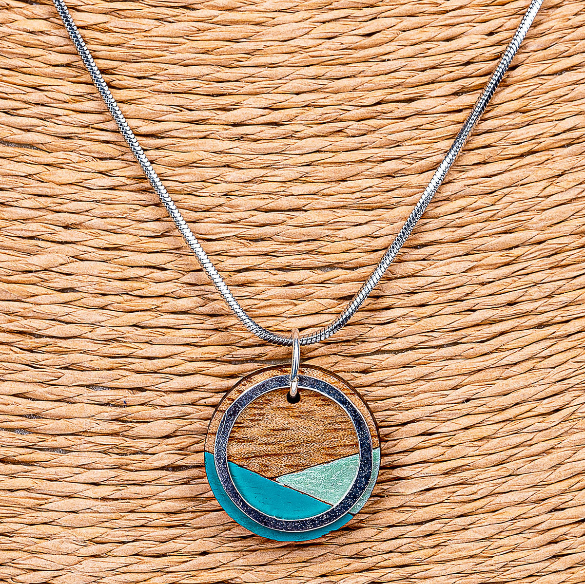 Paguro Upcycle recycled wood silver necklace with circular pendant and teal accents on silver chain