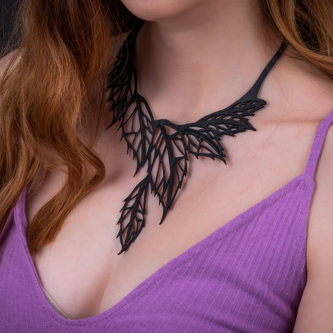 Paguro Upcycle recycled rubber leaf necklace worn with purple tank top showcasing intricate black leaf design